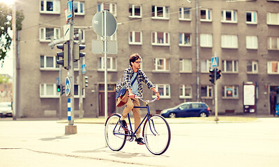 Image showing young hipster man with bag riding fixed gear bike