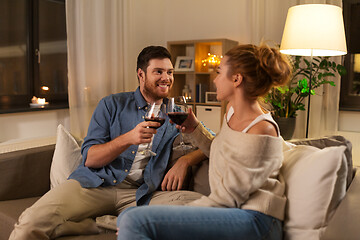 Image showing happy couple drinking red wine at home in evening