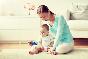 Image showing happy mother showing smartphone to baby at home