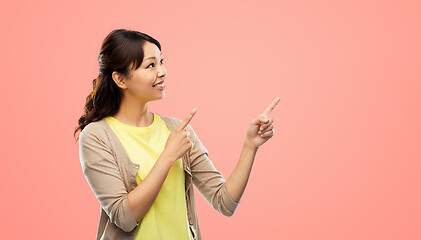 Image showing happy asian woman pointing fingers up