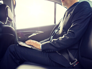 Image showing senior businessman with laptop driving in car