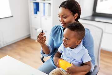 Image showing mother with baby son holding medicine at clinic