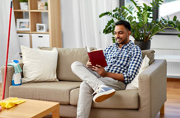 Image showing man reading book and resting after home cleaning