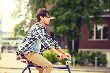 Image showing young hipster man with bag riding fixed gear bike