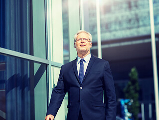 Image showing senior businessman walking along city street