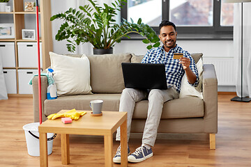 Image showing man with laptop shopping online after cleaning