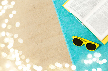 Image showing sunglasses and book on beach towel on sand