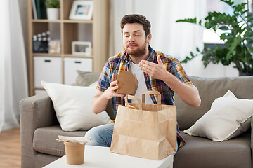 Image showing smiling man unpacking takeaway food at home