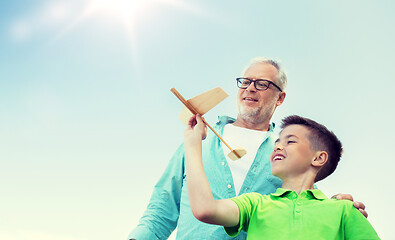 Image showing senior man and boy with toy airplane over sky