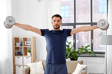 Image showing smiling man exercising with dumbbells at home