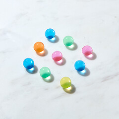 Image showing Diagonal pattern from hydrogel color balls on a grey marble table.