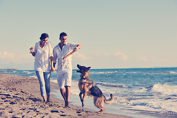 Image showing happy family playing with dog on beach