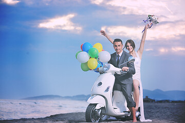 Image showing just married couple on the beach ride white scooter