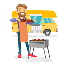 Image showing Young man barbecuing meat in front of camper van.