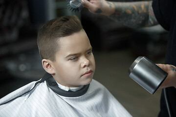 Image showing Children hairdresser cutting little boy against a dark background.