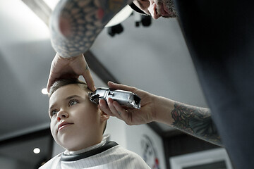 Image showing Children hairdresser cutting little boy against a dark background.