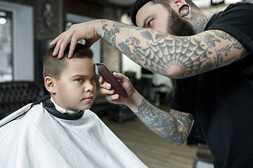 Image showing Children hairdresser cutting little boy against a dark background.