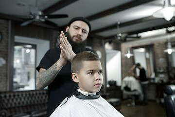 Image showing Children hairdresser cutting little boy against a dark background.