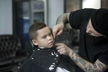 Image showing Children hairdresser cutting little boy against a dark background.