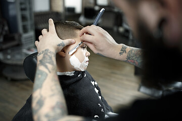 Image showing Children hairdresser cutting little boy against a dark background.