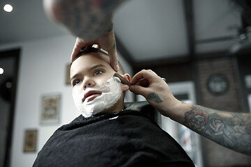 Image showing Children hairdresser cutting little boy against a dark background.