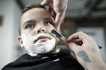 Image showing Children hairdresser cutting little boy against a dark background.