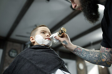 Image showing Children hairdresser cutting little boy against a dark background.