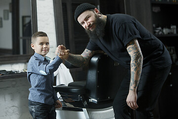 Image showing Children hairdresser cutting little boy against a dark background.