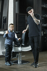 Image showing Children hairdresser cutting little boy against a dark background.