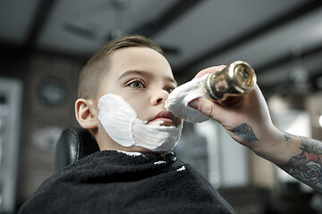 Image showing Children hairdresser cutting little boy against a dark background.