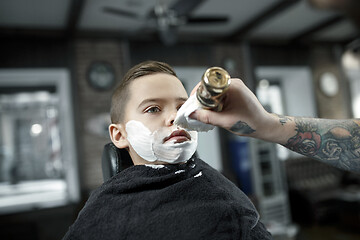 Image showing Children hairdresser cutting little boy against a dark background.