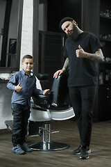 Image showing Children hairdresser cutting little boy against a dark background.