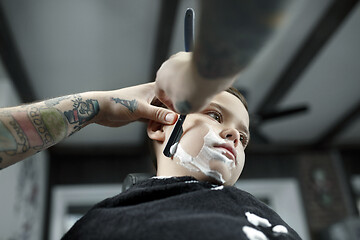 Image showing Children hairdresser cutting little boy against a dark background.