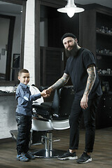 Image showing Children hairdresser cutting little boy against a dark background.