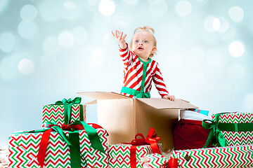 Image showing Cute baby girl 1 year old sitting at box over Christmas background. Holiday season.