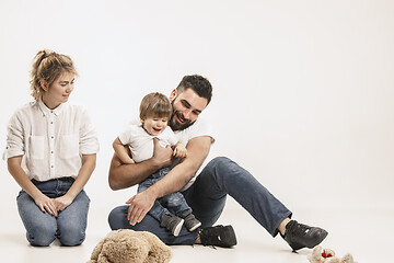 Image showing happy family with kid sitting together and smiling at camera isolated on white