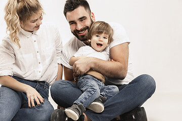 Image showing happy family with kid sitting together and smiling at camera isolated on white