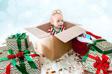 Image showing Cute baby girl 1 year old sitting at box over Christmas background. Holiday season.