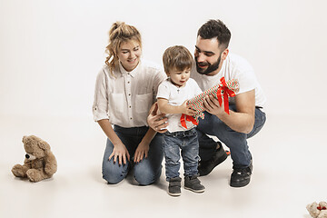 Image showing happy family with kid sitting together and smiling at camera isolated on white