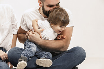 Image showing happy family with kid sitting together and smiling at camera isolated on white