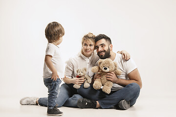 Image showing happy family with kid sitting together and smiling at camera isolated on white