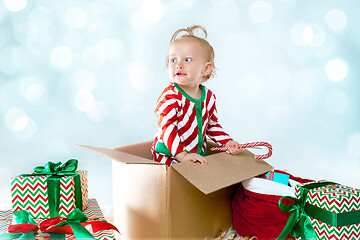 Image showing Cute baby girl 1 year old sitting at box over Christmas background. Holiday season.