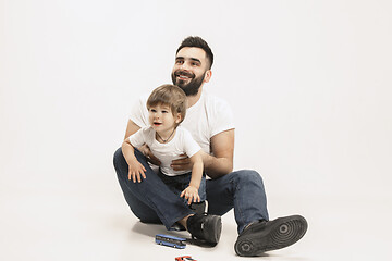 Image showing happy family with kid sitting together and smiling at camera isolated on white