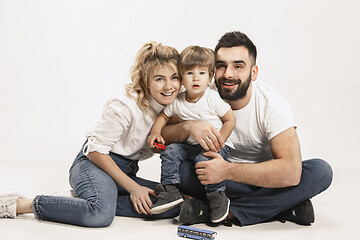 Image showing happy family with kid sitting together and smiling at camera isolated on white