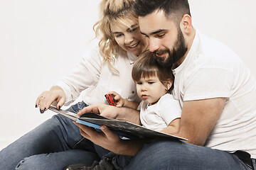 Image showing happy family with kid sitting together and smiling at camera isolated on white