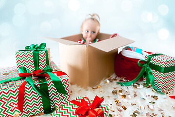 Image showing Cute baby girl 1 year old sitting at box over Christmas background. Holiday season.