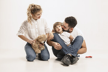 Image showing happy family with kid sitting together and smiling at camera isolated on white