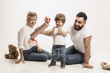 Image showing happy family with kid sitting together and smiling at camera isolated on white