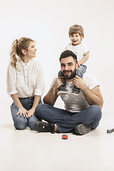 Image showing happy family with kid sitting together and smiling at camera isolated on white