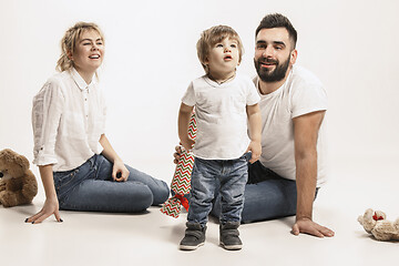 Image showing happy family with kid sitting together and smiling at camera isolated on white